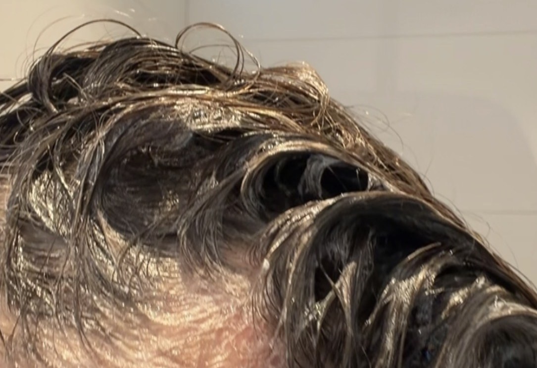 Kopfhautpeeling im nassen Haar, auf der Kopfhaut verteilt und aufemulgiert